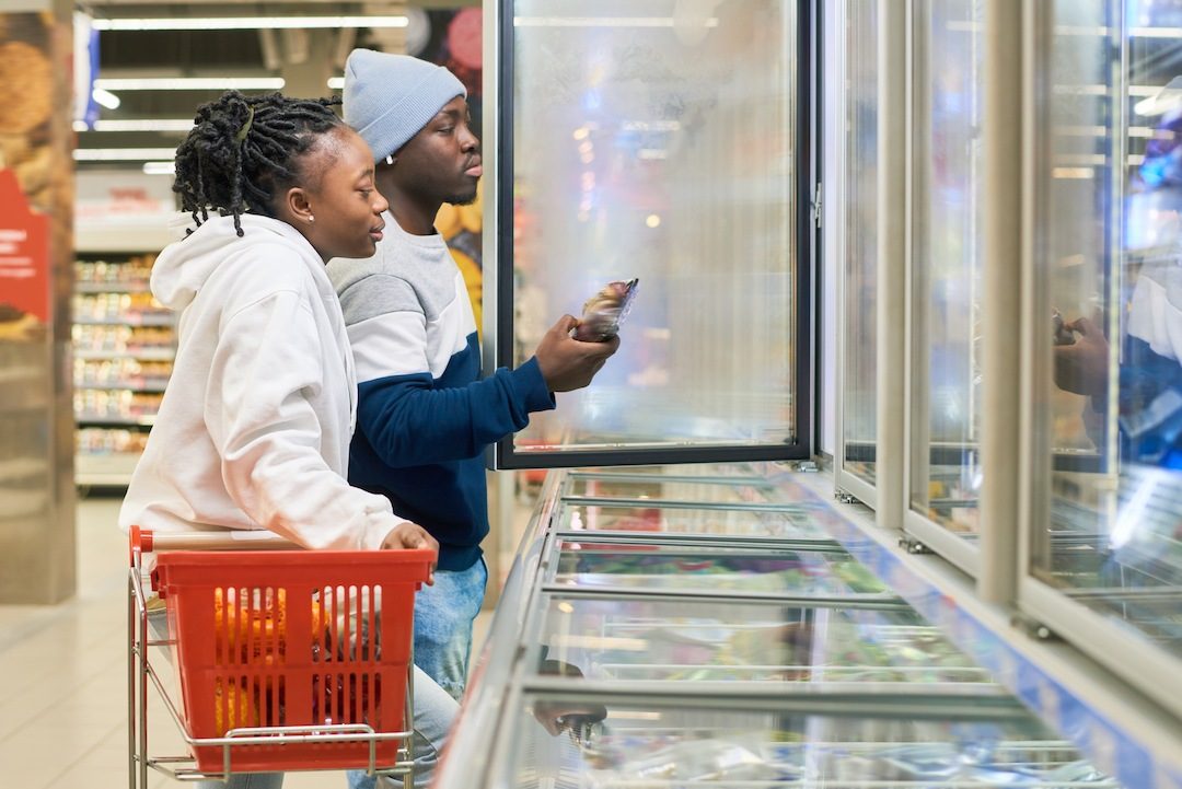 young couple with shopping cart choosing frozen food